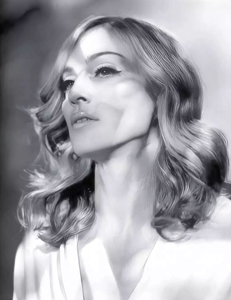 A close-up black and white portrait of a woman with wavy hair, looking upwards with a serene expression, highlighted by soft lighting and shadows.
