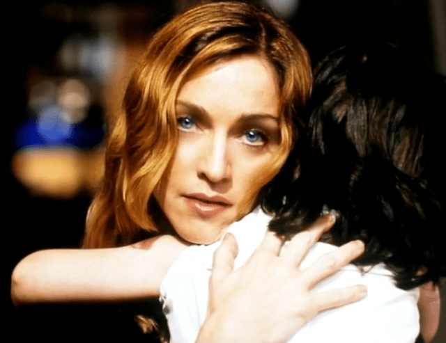 A woman with long, wavy hair holds a child close to her, expressing a moment of tenderness and connection.