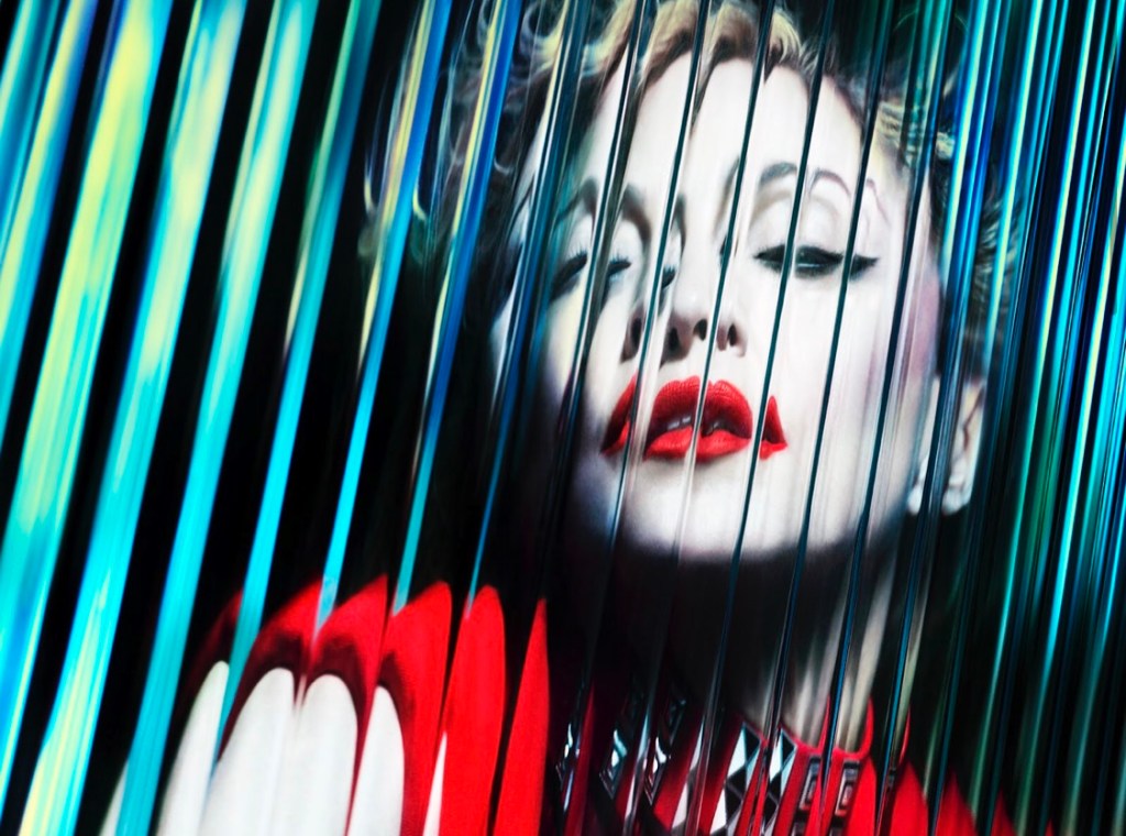 A close-up portrait of a woman with bold red lips and dramatic eye makeup, framed by colorful reflective strips.