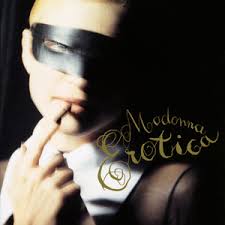 Close-up of a person wearing a black mask and giving a suggestive gesture with their finger, with the text 'Madonna Erotica' in elegant gold lettering.