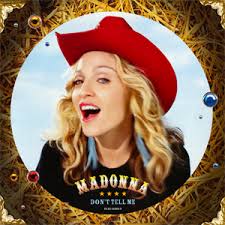 A smiling woman with long wavy blonde hair wearing a red cowboy hat and earrings, set against a decorative background with a circular frame.