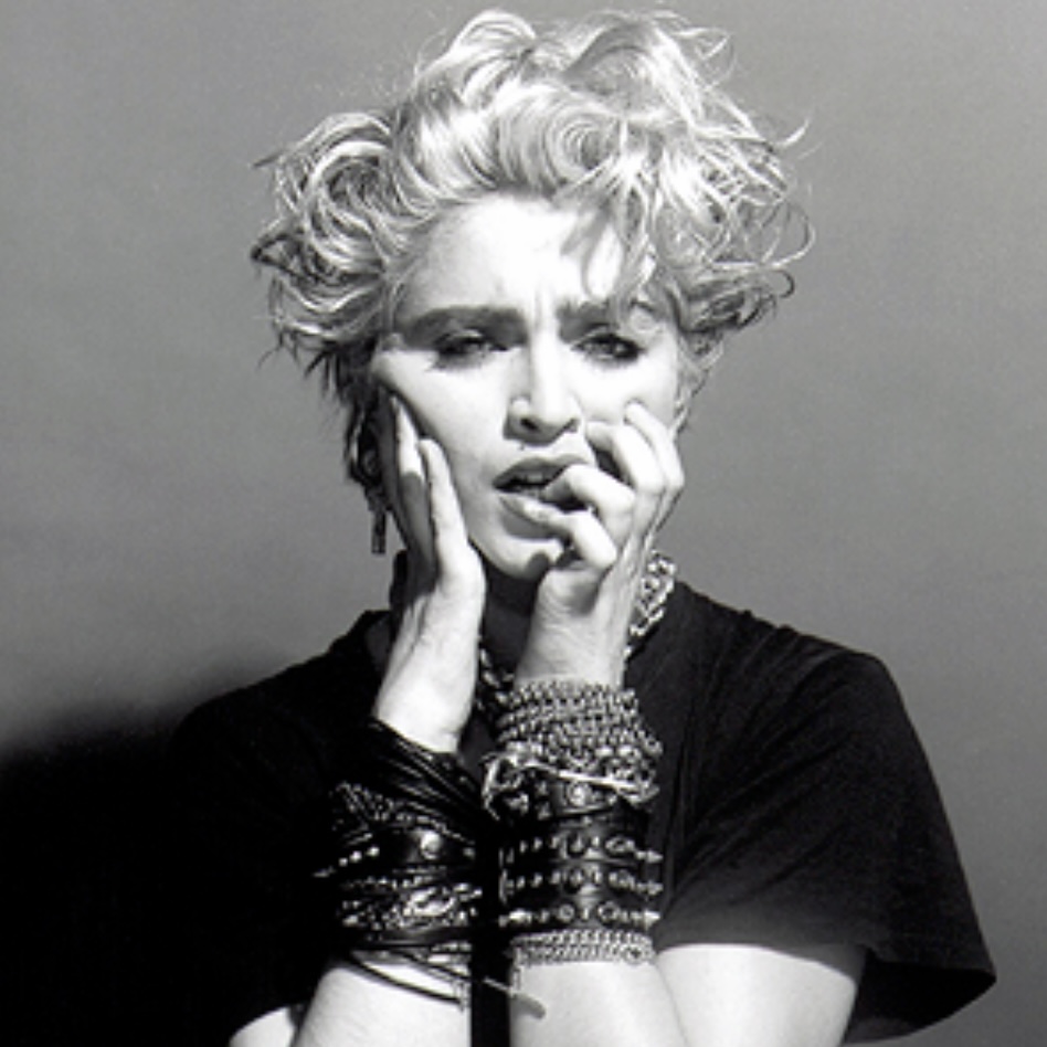 A black and white portrait of a woman with short, curly hair and multiple bracelets, looking distressed with her hands on her face.