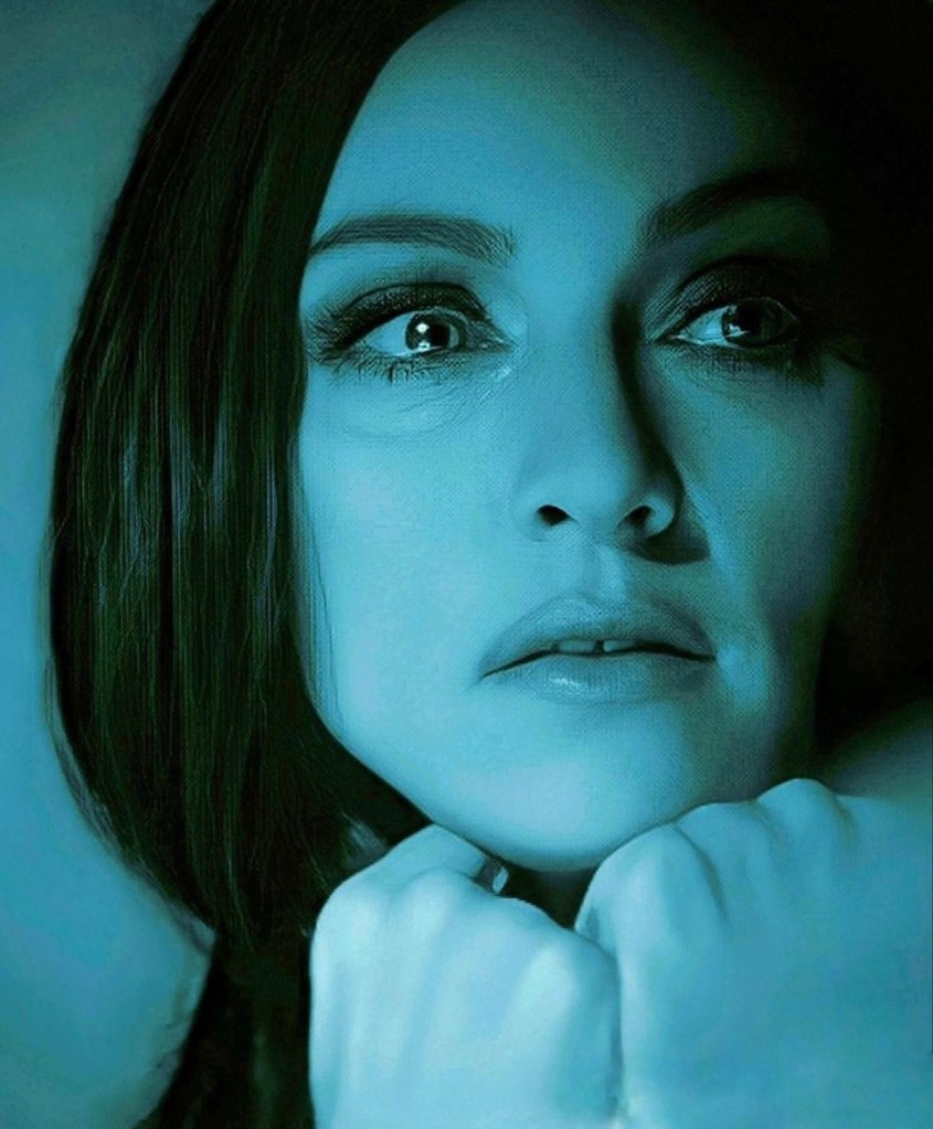 Close-up portrait of a woman with long dark hair, illuminated in blue tones, showing a contemplative expression.