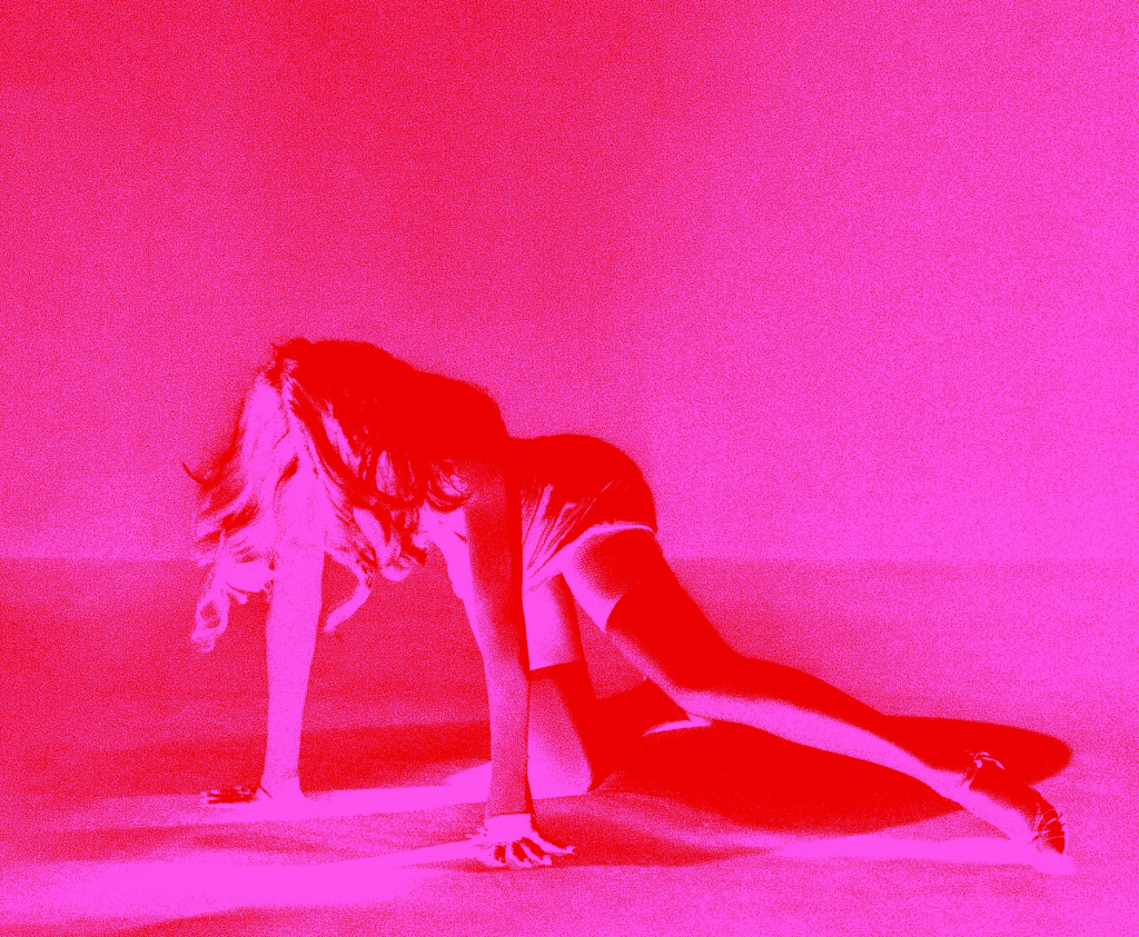 A woman in a playful pose on all fours, against a vibrant pink background.