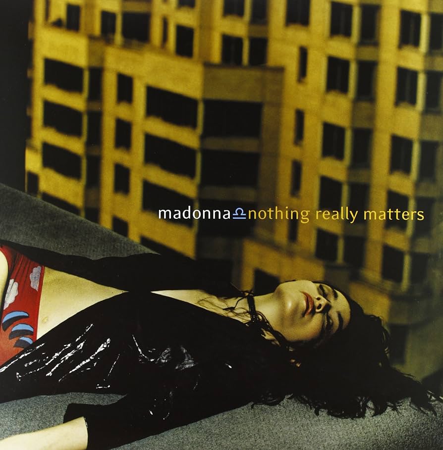 Album cover for Madonna's song 'Nothing Really Matters', featuring a close-up image of a woman lying down with a city backdrop.