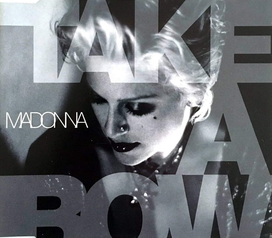 Black and white album cover featuring a close-up of a woman with light-colored hair and dark makeup, overlaid with the text 'TAKE A BOW' and 'MADONNA'.