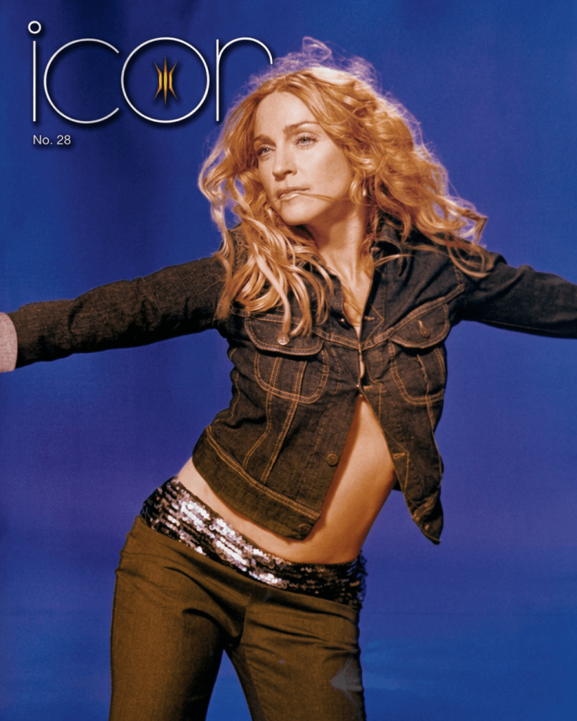 A model in a denim jacket and sequined pants posing against a blue background for the cover of Icon magazine, issue No. 28.