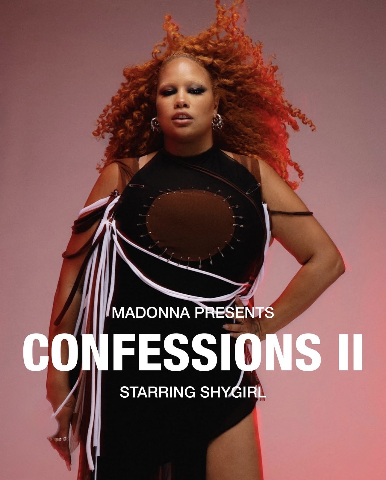 A person with curly red hair poses confidently in a black outfit adorned with white ribbons. The image features bold text reading 'MADONNA PRESENTS CONFESSIONS II STARRING SHYGIRL' against a gradient background.